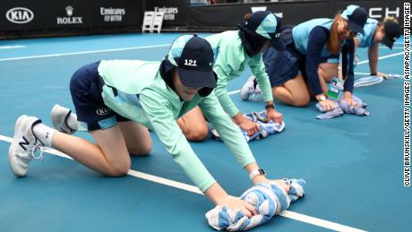 Staff clean dirt off the outside courts at Melbourne Park