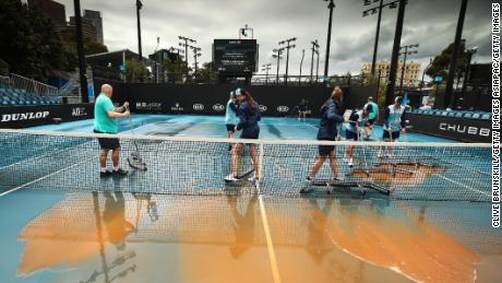 MELBOURNE, AUSTRALIA - JANUARY 23: (EDITORS NOTE: A graduated grey filter was used to create this image.) Staff are seen attempting to clean dirt off the outside courts after being caused by rainfall on day four of the 2020 Australian Open at Melbourne Park on January 23, 2020 in Melbourne, Australia. (Photo by Clive Brunskill/Getty Images)