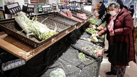 Residents wear masks to buy vegetables in a market in Wuhan.