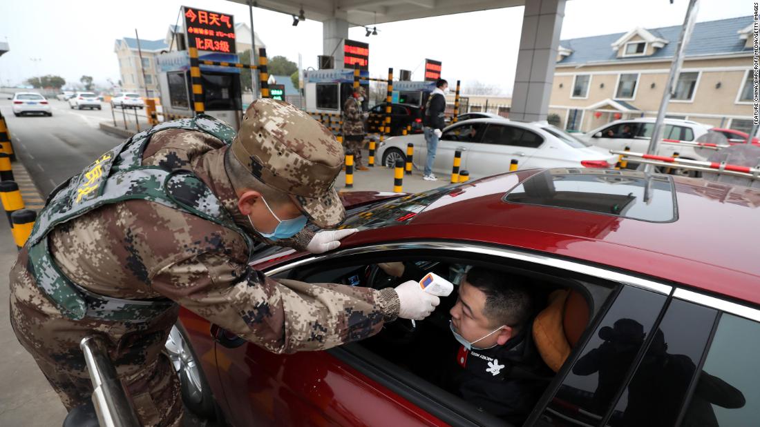 A militia member checks the body temperature of a driver in Wuhan on January 23.