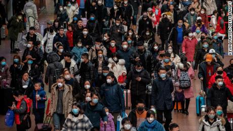 Chinese passengers, most wearing masks, arrive to board trains before the annual Spring Festival at a Beijing railway station.