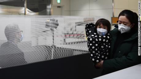 Passengers who arrived on one of the last flights from the Chinese city of Wuhan walk through a health screening station at Narita airport in Chiba prefecture, outside Tokyo, on January 23, 2020.