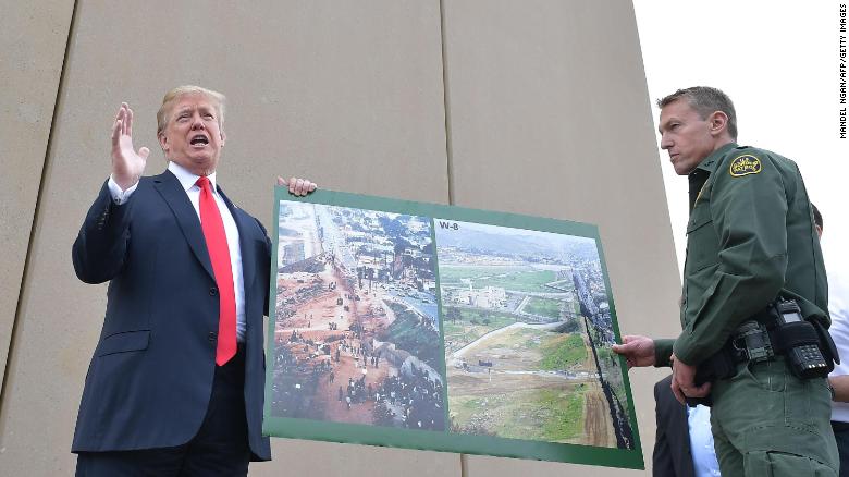 US President Donald Trump holds up a poster of before and after photos of a segment of the  border wall prototypes with Chief Patrol Agent Rodney S. Scott in San Diego, California on March 13, 2018. 