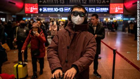 A Chinese man wears a protective mask and goggles before boarding a train at a Beijing railway station on January 23, 2020.