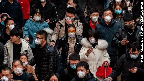 Chinese passengers, almost all wearing protective masks, arrive to board trains before the annual Spring Festival at a Beijing railway station on January 23, 2020.