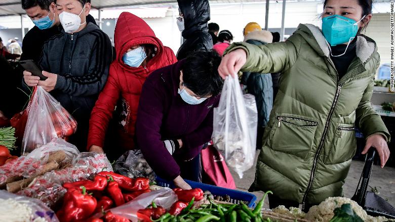 Residents wear masks to buy vegetables at a market in Wuhan on January 23, 2020.