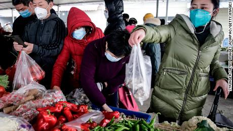 Residents wear masks to buy vegetables at a market in Wuhan on January 23, 2020.