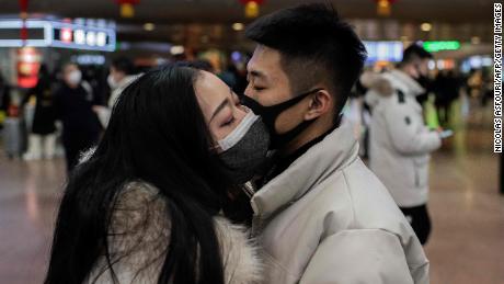 A couple, wearing protective masks, kisses goodbye as they travel for the Lunar New Year holidays at a railway station in Beijing.