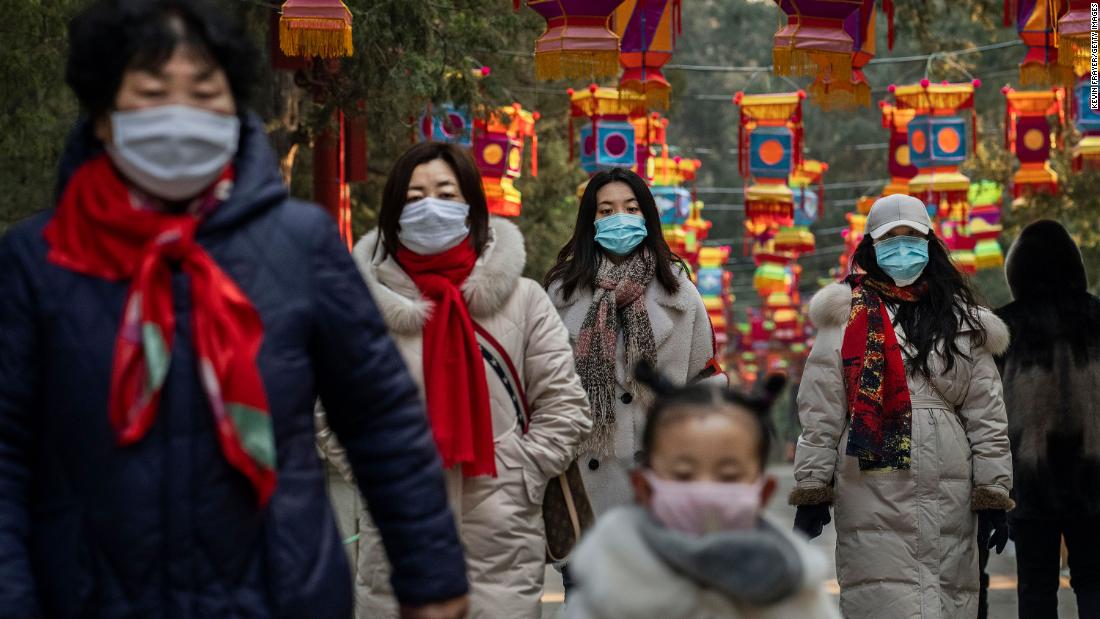 People wear protective masks as they walk under Lunar New Year decorations in Beijing on January 25.