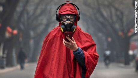 A Chinese man wears a protective mask, goggles and coat as he stands in a nearly empty street during the Chinese New Year holiday in Beijing.