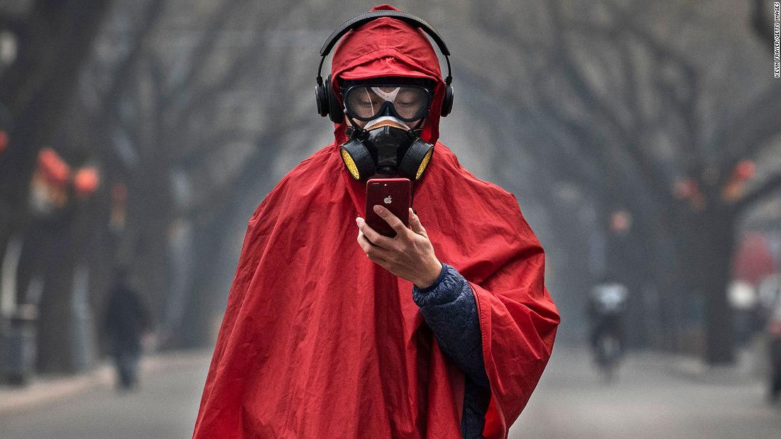 A person wears a protective mask, goggles and coat as he stands in a nearly empty street in Beijing on January 26, 2020.