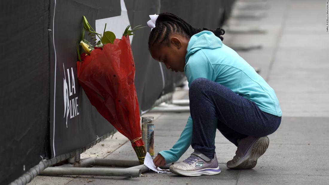 Dharma Brown, 8, writes a note to the late Bryant outside of the Staples Center in Los Angeles on Sunday.