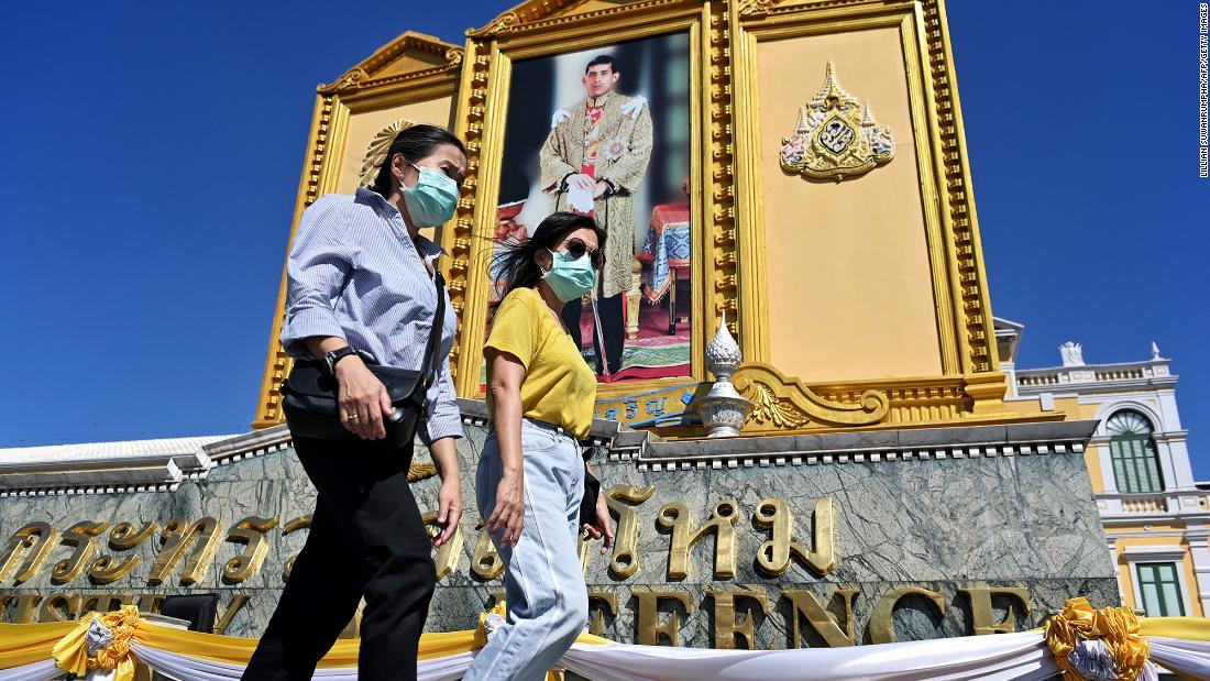 People wearing masks walk past a portrait of Thailand's King Maha Vajiralongkorn near the Grand Palace in Bangkok on January 27.