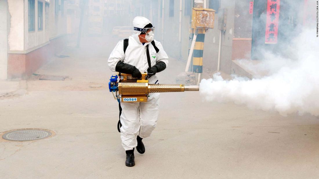 A volunteer wearing protective clothing disinfects a street in Qingdao, China, on January 29, 2020.