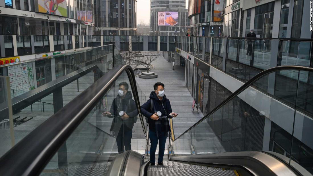 A man wearing a protective mask rides an escalator in a shopping area that would usually be busy during the Chinese New Year in Beijing, on January 28.