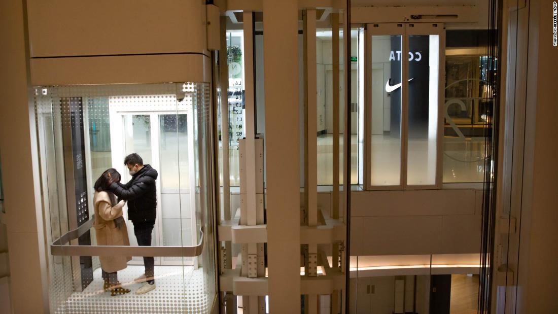 A couple wearing face masks ride an elevator at a nearly empty shopping mall in Beijing on January 29.