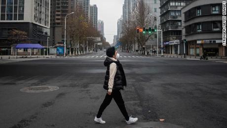 A woman crosses an empty street in Wuhan. The city has been under lockdown since January 23.