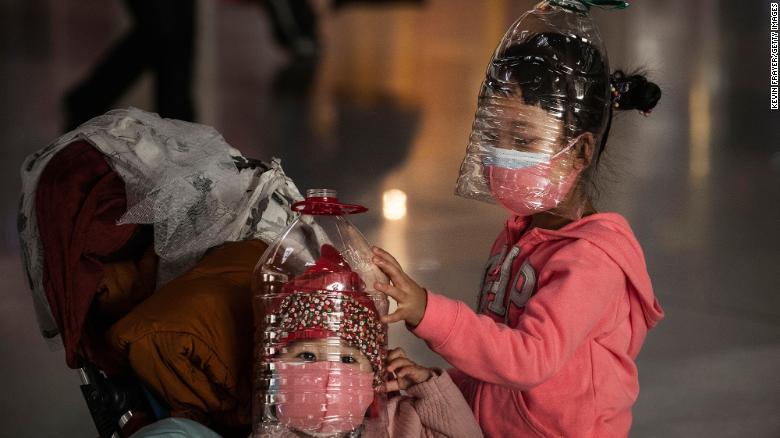 Chinese children wear plastic bottles as makeshift homemade protection and protective masks while waiting to check in to a flight at Beijing Capital Airport on Thursday, January 30 in Beijing, China. 