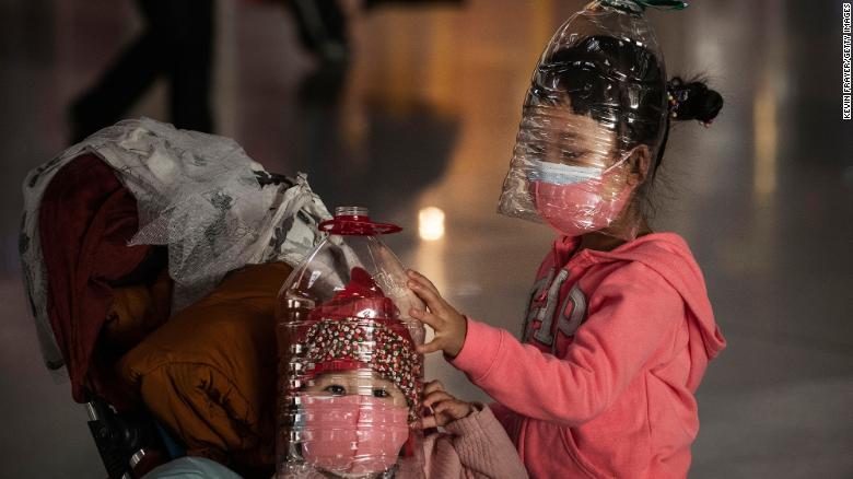 I bambini cinesi indossano bottiglie di plastica come protezione improvvisata fatta in casa e maschere protettive in attesa di effettuare il check-in per un volo all'aeroporto di Pechino, giovedì 30 gennaio a Pechino, Cina. 