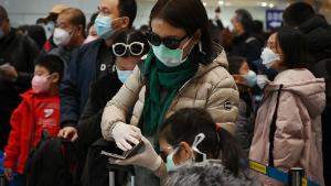 A woman wears a protective face mask and gloves while waiting to go through immigration at Beijing airport on February 1, 2020. - China faced deepening isolation over its coronavirus epidemic on February 1 as the death toll soared to 259, with the United States leading a growing list of nations to impose extraordinary Chinese travel bans. (Photo by GREG BAKER / AFP) (Photo by GREG BAKER/AFP via Getty Images)