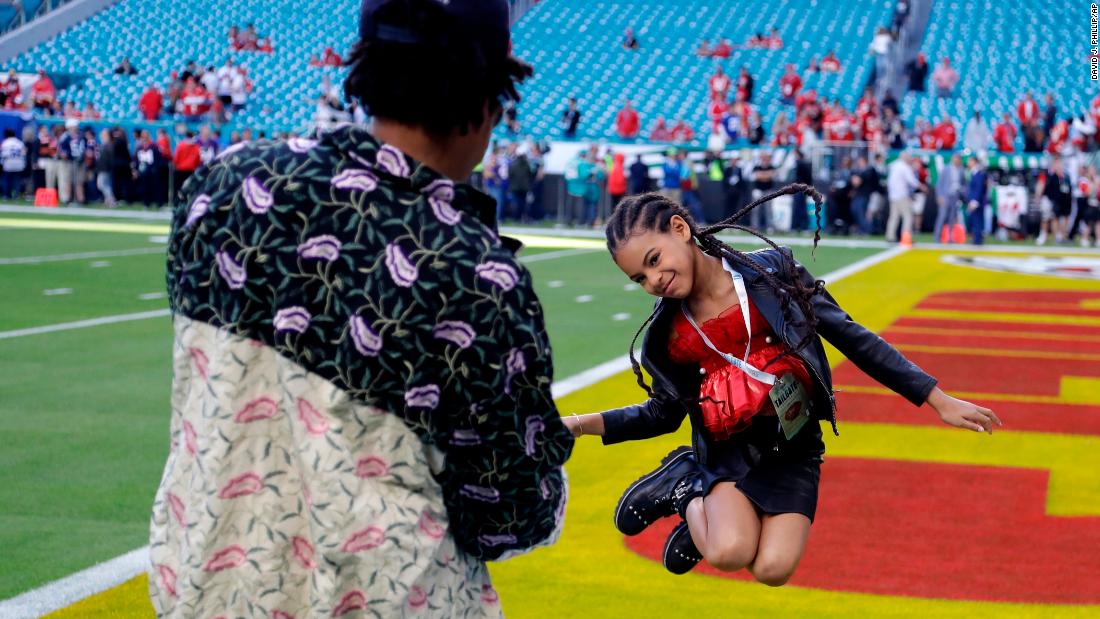 Rapper Jay-Z watches his daughter, Blue Ivy, leap on the field before the game.