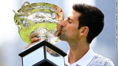 Djokovic stands with the trophy after winning the 2020 Australian Open.