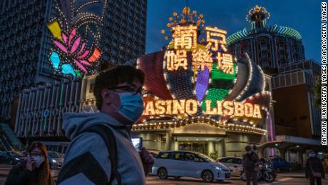 People wearing face masks walk in front of the Grand Lisboa Hotel on January 28, 2020 in Macao.