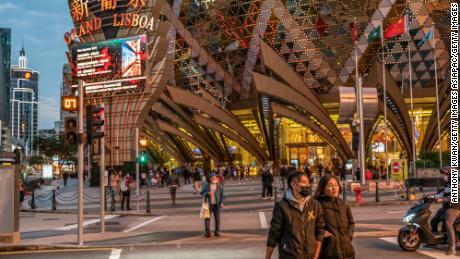 People wearing face masks walk in front of the Grand Lisboa Hotel on January 28, 2020 in Macao.