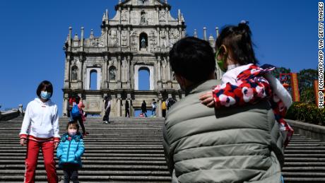 People wear protective facemasks visiting Largo da Companhia de Jesus with the background of Ruínas de São Paulo in Macao on January 30, 2020. 