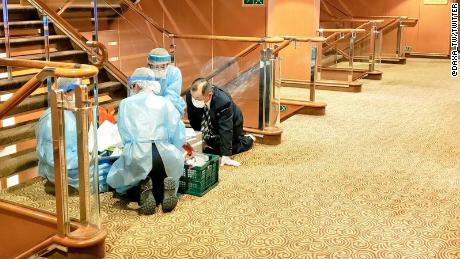 Health workers are seen on board the Diamond Princess in this photograph taken by a passenger.