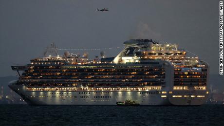 A small boat is pictured next to the Diamond Princess cruise ship as it sits anchored.