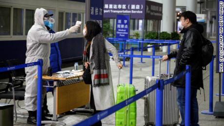 A security personnel checks the temperature of passengers arriving at the Shanghai Pudong International Airport.