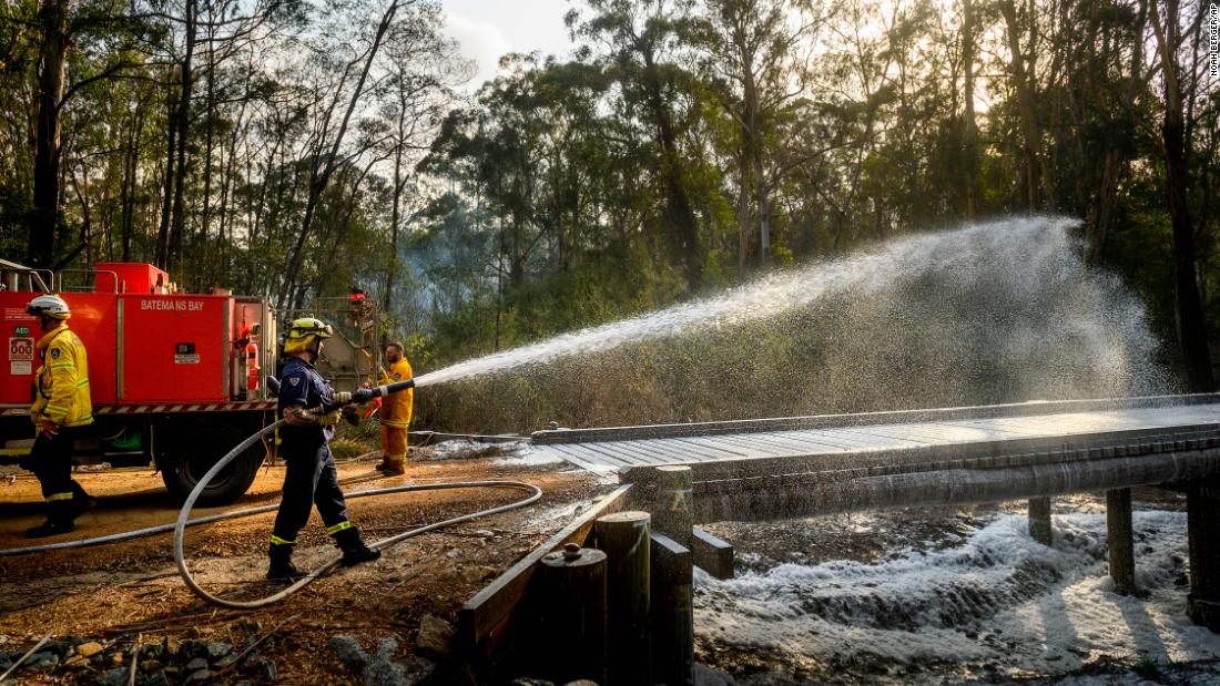 A firefighter coats a bridge with foam as a bushfire burns near Moruya, Australia, on Saturday, January 25.