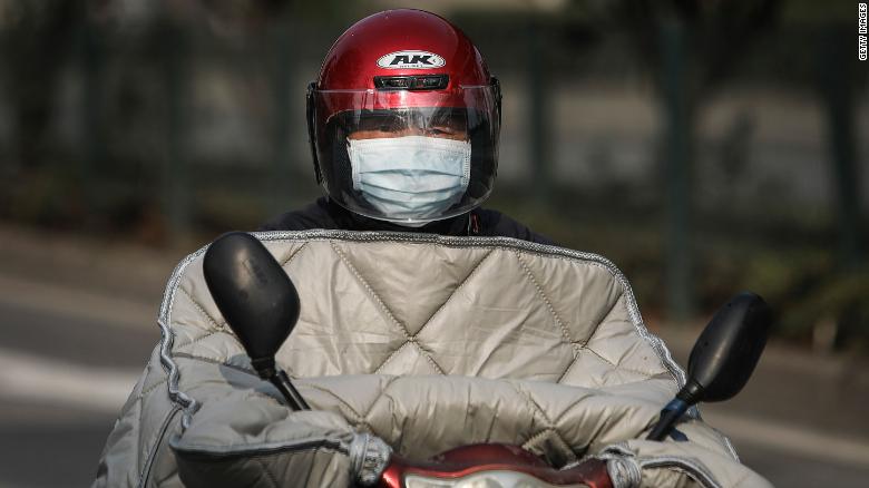 A resident wears a protective mask while riding a scooter on February 5, 2020, in Wuhan.