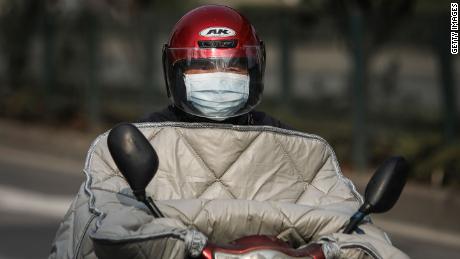 A resident wears a protective mask while riding a scooter on February 5, 2020, in Wuhan.