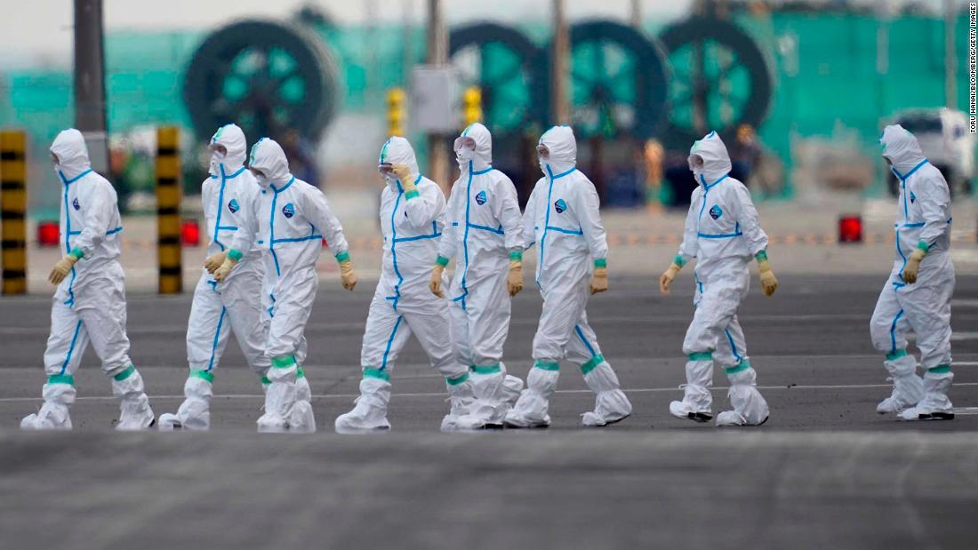 Workers in protective gear walk near the Diamond Princess cruise ship docked in Yokohama, Japan.