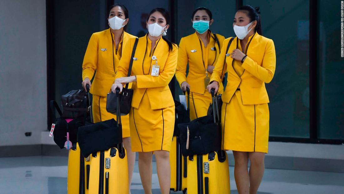 Flight attendants wearing face masks make their way through the Don Mueang Airport in Bangkok on February 7, 2020.