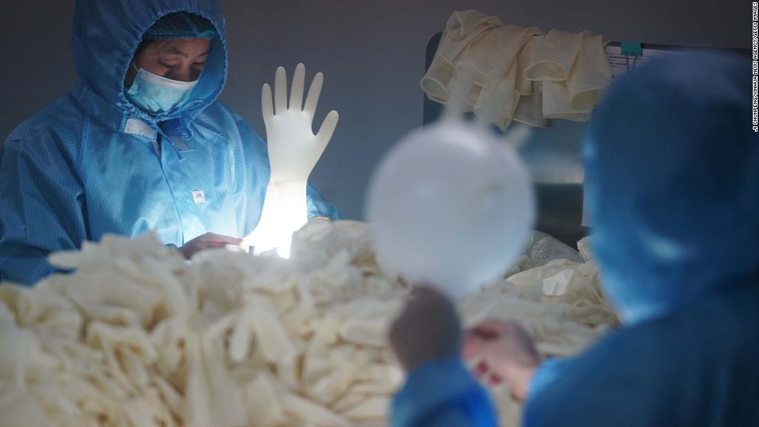 Workers check sterile medical gloves at a latex-product manufacturer in Nanjing, China, on February 6, 2020.