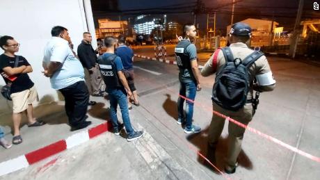 Police and members of the public stand near the Terminal 21 mall in Korat where a gunman was believed to be holed up.