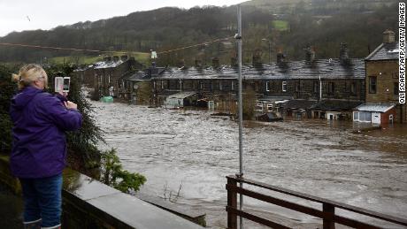 A woman photographs flooded houses in Mytholmroyd, northern England after the River Calder burst its banks. 