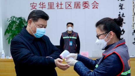 In this photo released by Xinhua News Agency, Chinese President Xi Jinping, left, wearing a protective face mask receives a temperature check as he inspects the novel coronavirus pneumonia prevention and control work at a neighbourhoods in Beijing, Monday, Feb. 10, 2020. China reported a rise in new virus cases on Monday, possibly denting optimism that its disease control measures like isolating major cities might be working, while Japan reported dozens of new cases aboard a quarantined cruise ship. (Pang Xinglei/Xinhua via AP)