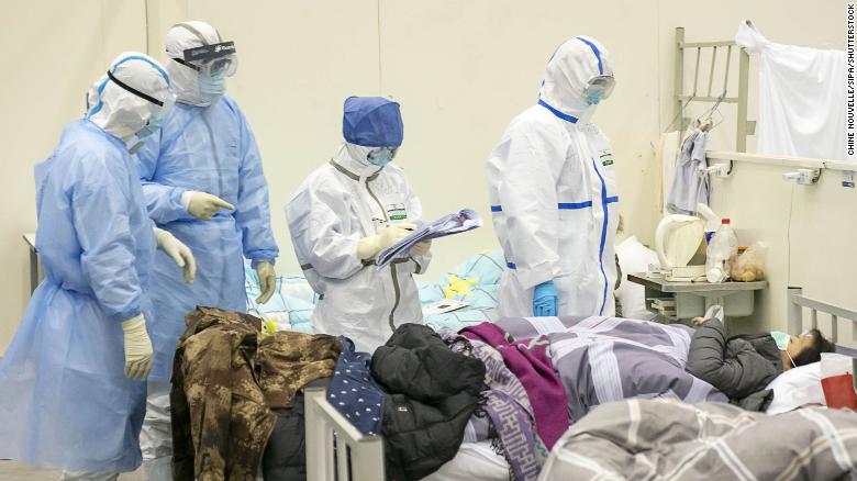 A equipe médica verifica a condição de um paciente em um hospital temporariamente convertido para pacientes com coronavírus em Wuhan.