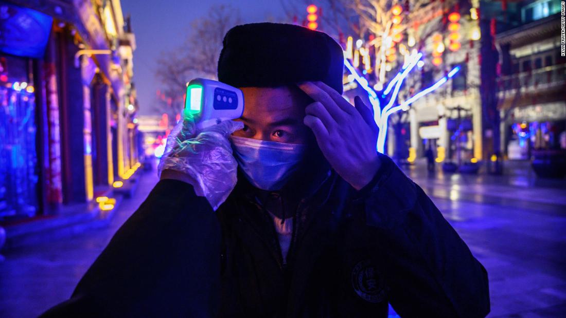 A worker has his temperature checked on a shuttered commercial street in Beijing on February 12, 2020.