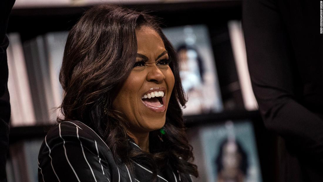 Obama laughs while signing copies of her memoir &quot;Becoming&quot; in November 2018. She&#39;d go on to win a best spoken word album Grammy for the audio version of her best-selling book.