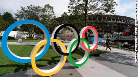 TOKYO, JAPAN - JULY 24: A woman walks past the Olympic rings displayed in front of the New National Stadium, the main venue for the Tokyo 2020 Olympic and Paralympic Games, under construction on July 24, 2019 in Tokyo, Japan. (Photo by Tomohiro Ohsumi/Getty Images)