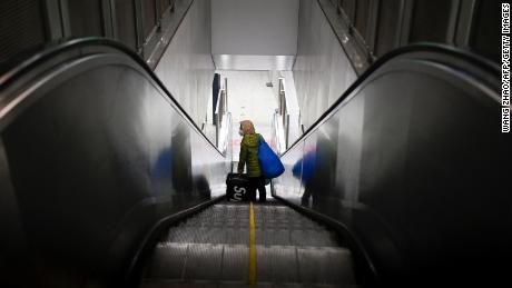 An elderly woman wearing a face mask rides an escalator at a subway station in Beijing on February 18, 2020. - The World Health Organization has warned against a global over-reaction to the new coronavirus epidemic following panic-buying, event cancellations and concerns about cruise ship travel, as China&#39;s official death toll neared 1,900 on February 18. (Photo by WANG ZHAO / AFP) (Photo by WANG ZHAO/AFP via Getty Images)