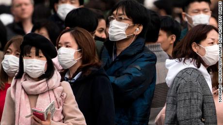  People wearing masks wait to cross a road  in the Shibuya district on February 02, 2020 in Tokyo, Japan