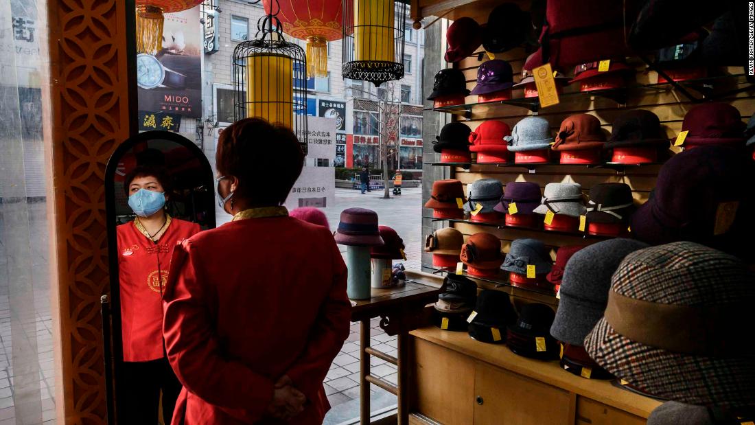 A sales clerk wears a mask as she waits for customers at a hat shop in Beijing on February 18, 2020.