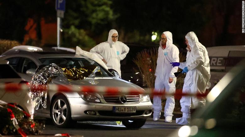 Forensic experts work around a damaged car after the attack in Hanau.