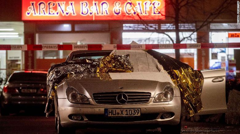 A car covered with rescue blankets stands in front of one of the bars that was attacked.